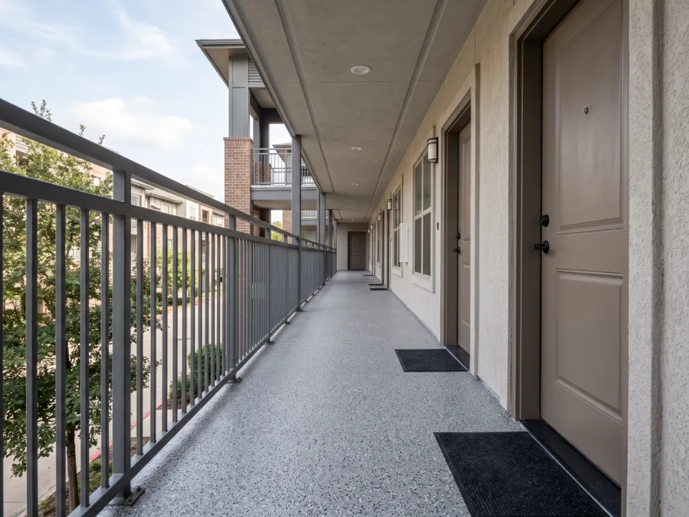 Second-floor apartment walkway with a fresh gray flake waterproof coating and metal railing