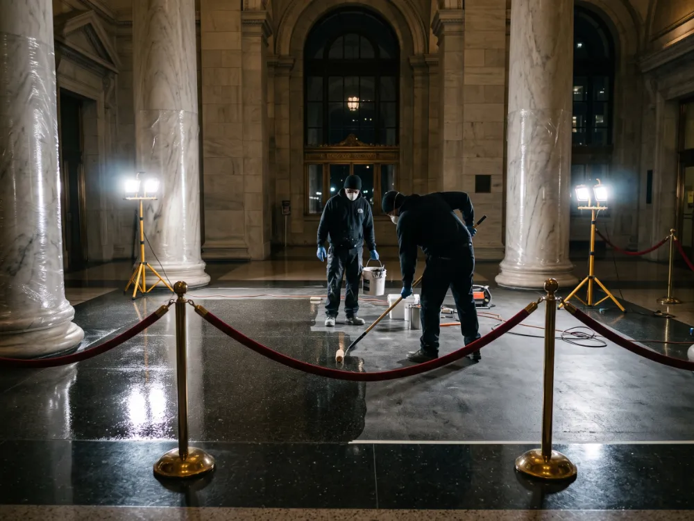 Technicians coating a civic lobby section behind barriers at night