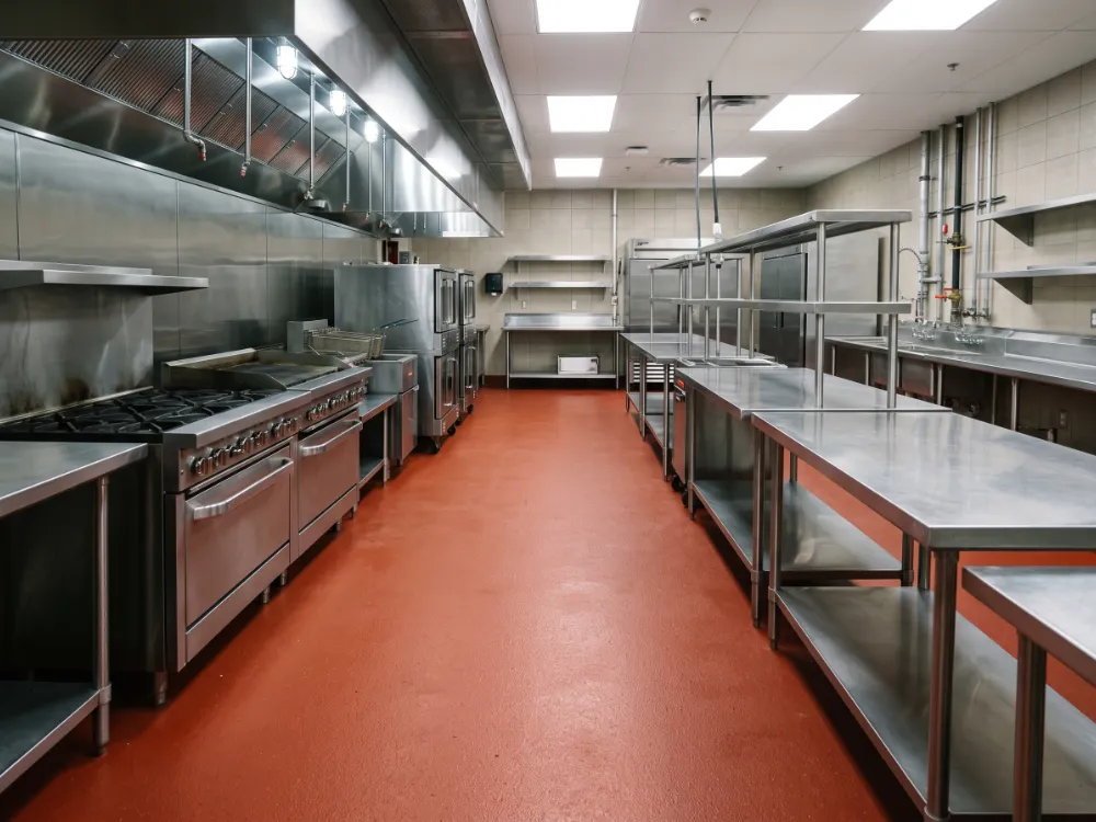Commercial kitchen line with a red urethane cement floor and seamless cove base