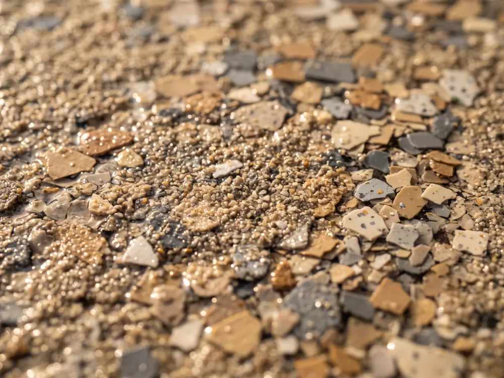 Warm tan and gray flake driveway surface with slip-resistant texture in raking sun