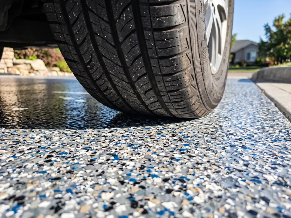 Car tire resting on a glossy coated flake driveway showing hot-tire resistance