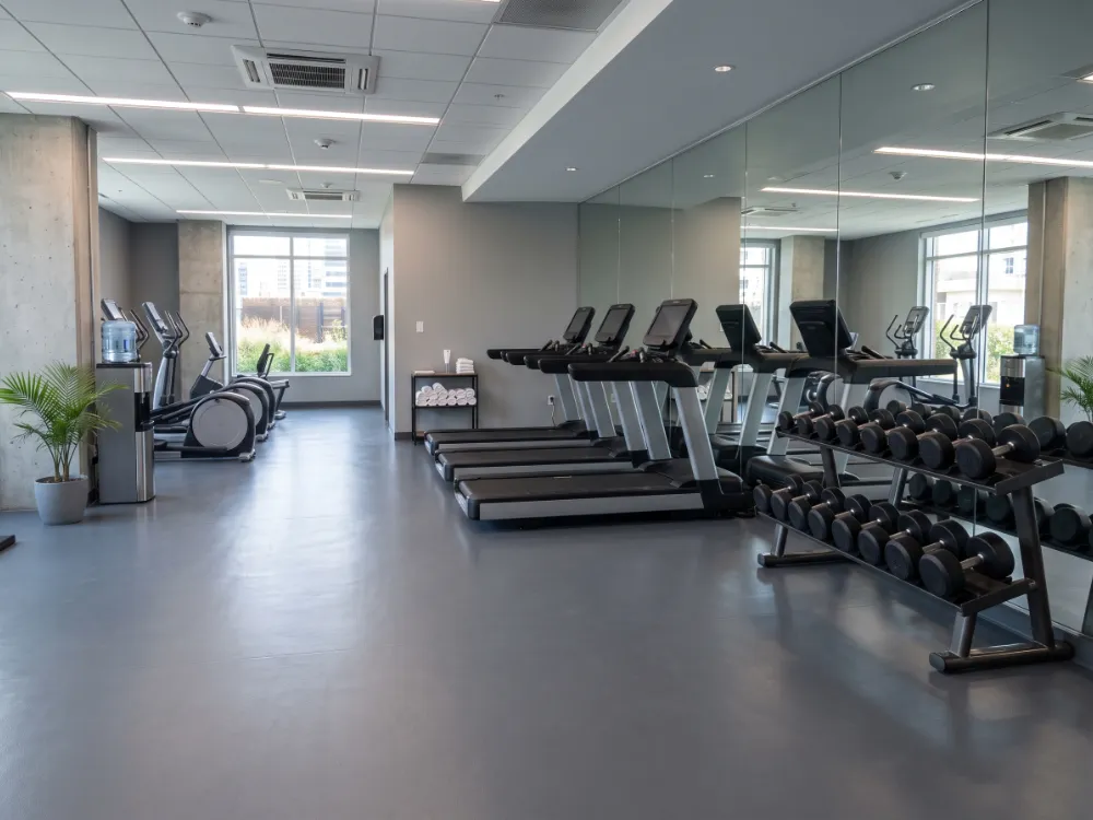 Hotel fitness room with a slate-gray epoxy floor beside mirrored wall