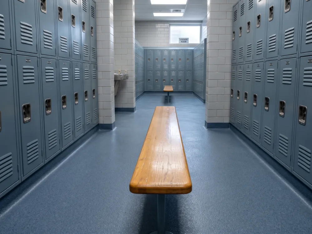 School locker room with a textured slate-blue epoxy floor and cove base