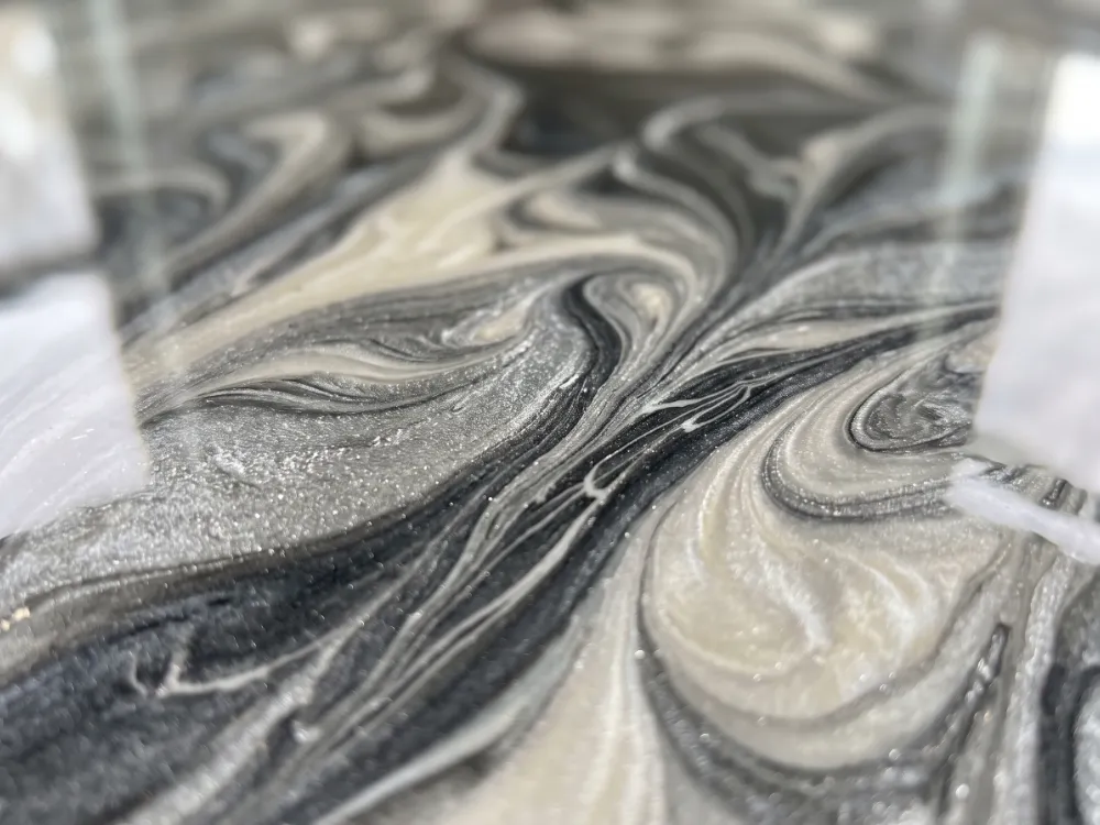 Close-up of pearl white silver and charcoal marbleized metallic epoxy swirls under gloss