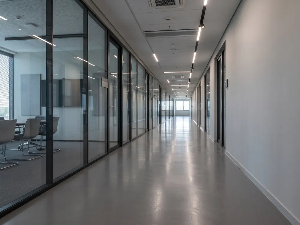 Office corridor with a seamless satin epoxy floor beside glass meeting rooms