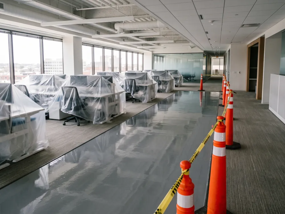 Fresh coated office floor section with desks under protective sheeting