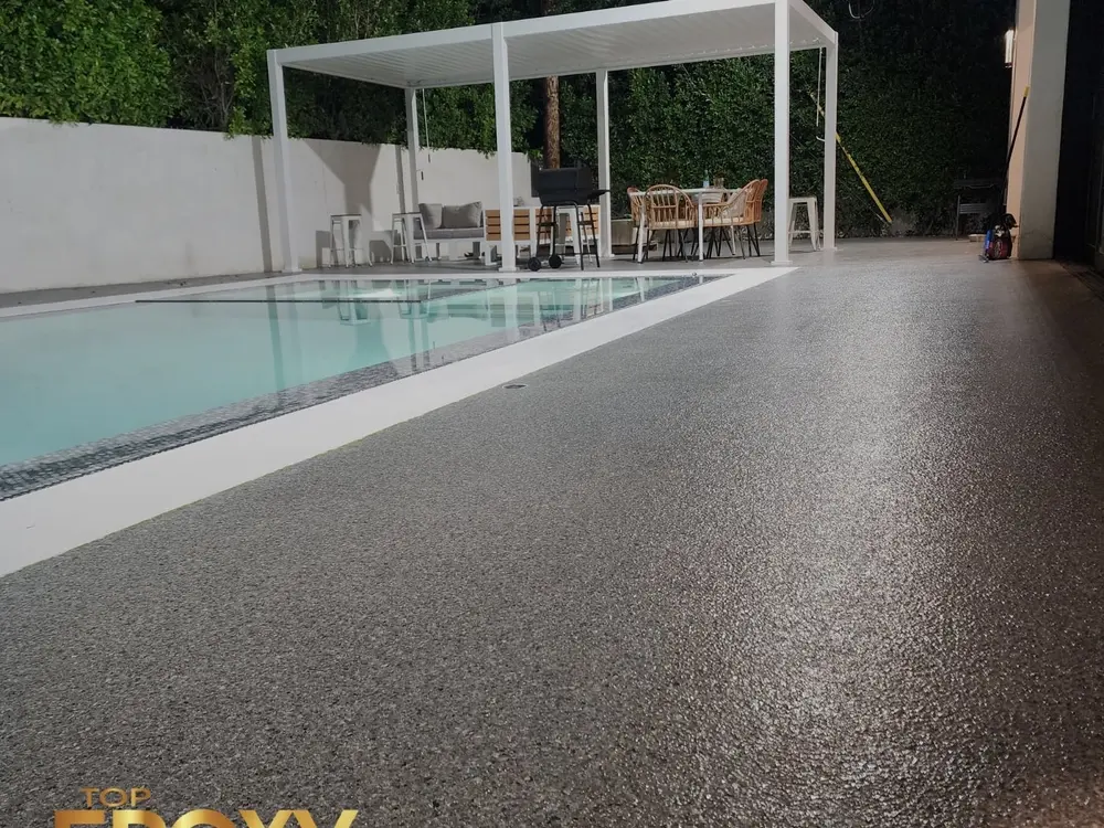 Pool deck coating Gray flake pool deck coating around a backyard pool in Sand Canyon