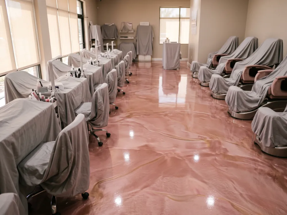 Blush-pink metallic epoxy settling into swirls in a salon with stations covered
