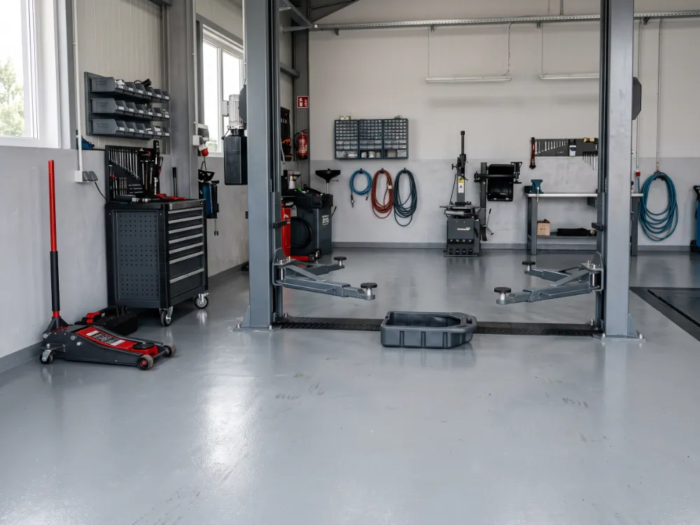 Service bay with a gray epoxy floor under a two-post lift