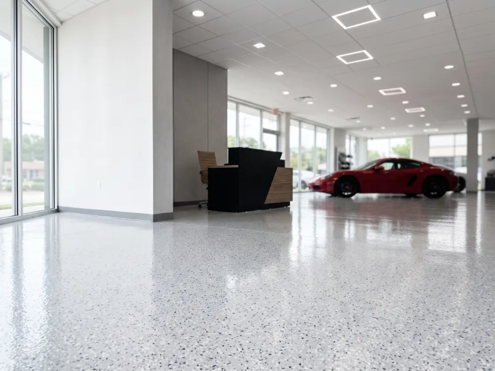 Automotive showroom with a light gray flake epoxy floor reflecting recessed lighting
