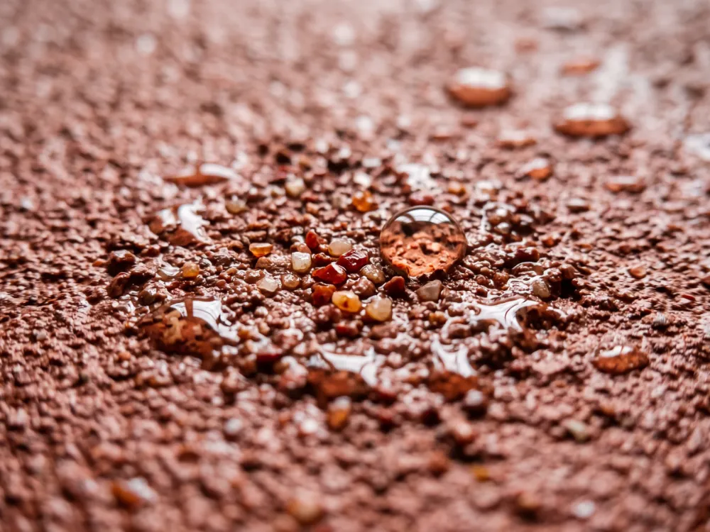 Slip-textured terracotta urethane cement surface with quartz broadcast and beading water