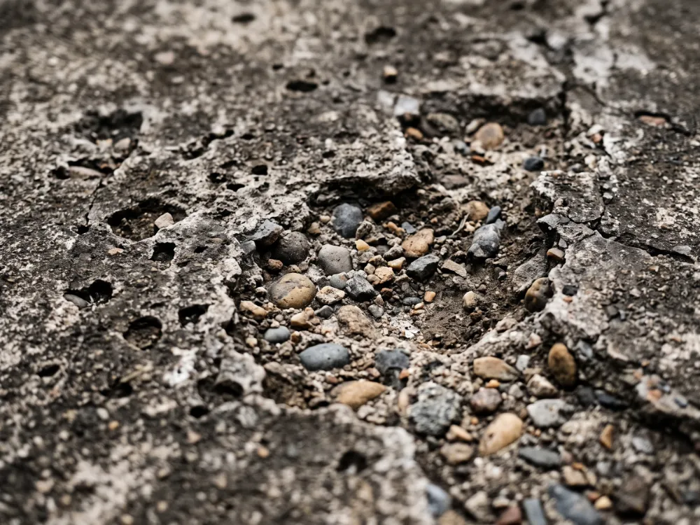 Severely spalled and pitted old concrete surface with exposed aggregate craters
