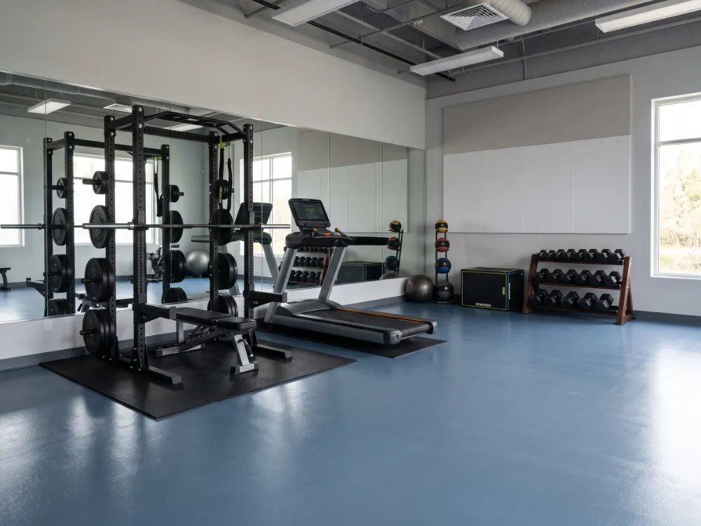 Fitness training room with a blue-gray epoxy floor and weight rack